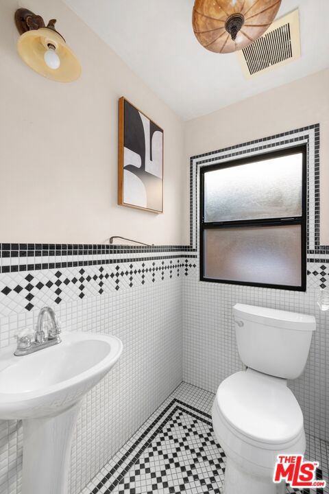 bathroom with tile walls, tile patterned floors, and toilet