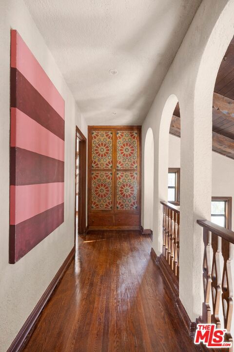 hallway with a textured ceiling, dark hardwood / wood-style floors, and french doors