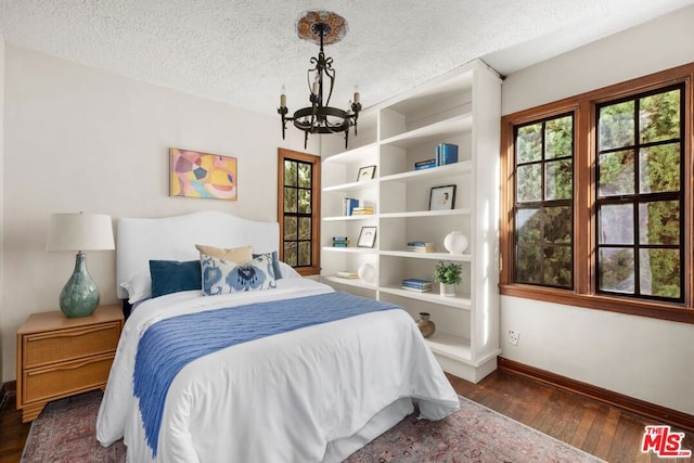 bedroom with a textured ceiling, dark hardwood / wood-style flooring, and a chandelier