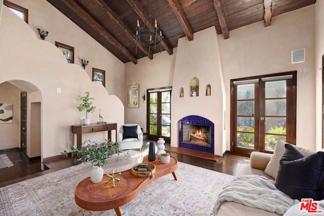 living room featuring dark wood-type flooring, french doors, high vaulted ceiling, a chandelier, and beamed ceiling