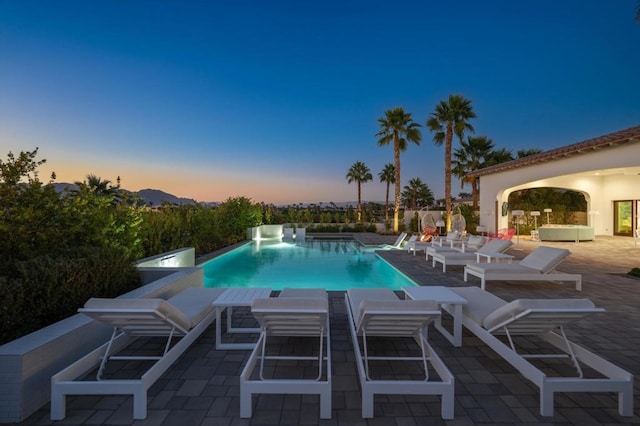 pool at dusk with a patio area