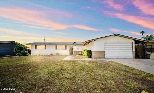 ranch-style home featuring a garage, a yard, and solar panels