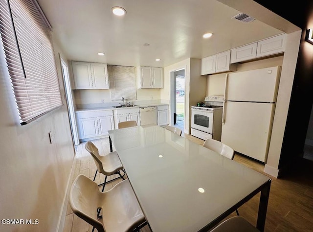 kitchen with white cabinetry, sink, white appliances, and a kitchen bar