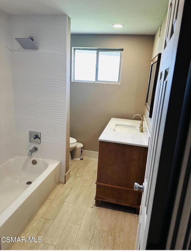 full bathroom featuring toilet, tiled shower / bath, and vanity