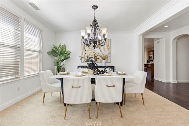 dining area featuring hardwood / wood-style flooring, crown molding, and an inviting chandelier