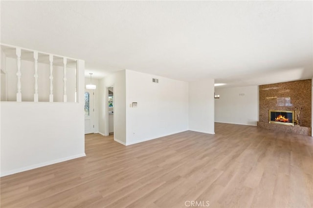 unfurnished living room featuring a large fireplace and light hardwood / wood-style flooring