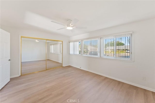 unfurnished bedroom with ceiling fan, a closet, and light wood-type flooring