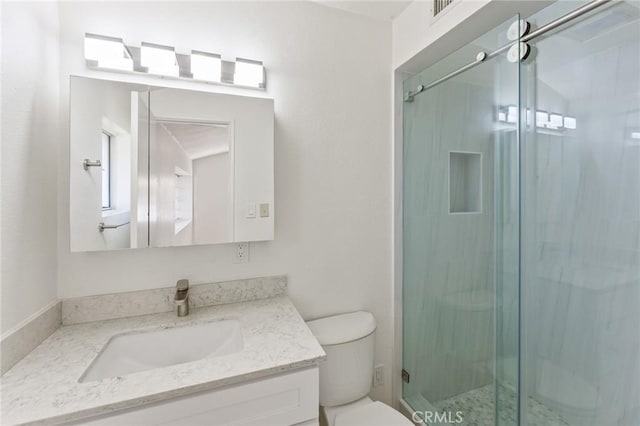 bathroom featuring a shower with door, toilet, and vanity