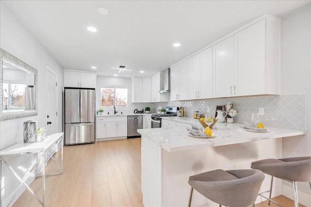 kitchen with a breakfast bar, kitchen peninsula, appliances with stainless steel finishes, and white cabinetry