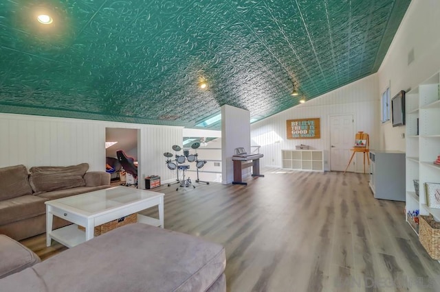 living room with vaulted ceiling, wooden walls, and hardwood / wood-style flooring