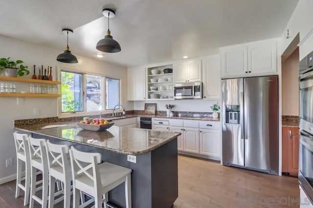 kitchen featuring decorative light fixtures, kitchen peninsula, appliances with stainless steel finishes, and white cabinetry