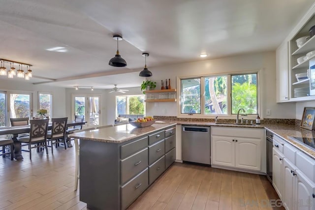 kitchen featuring stainless steel dishwasher, kitchen peninsula, white cabinets, and sink