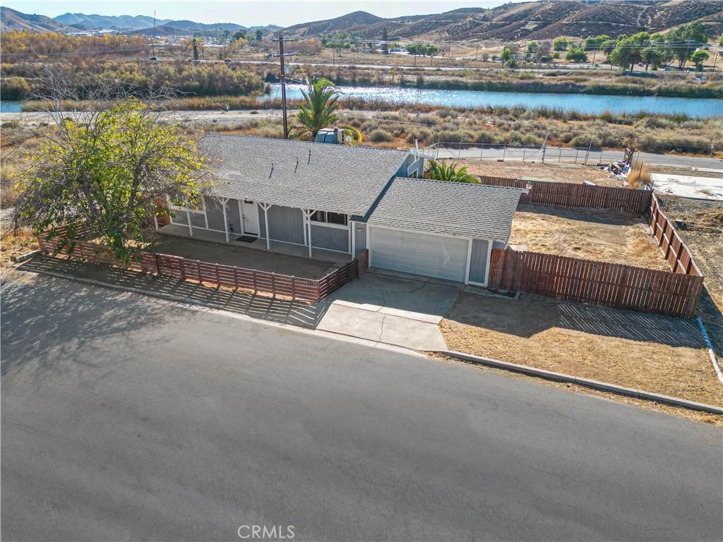 view of front facade featuring a fenced front yard, a garage, a shingled roof, driveway, and a water and mountain view