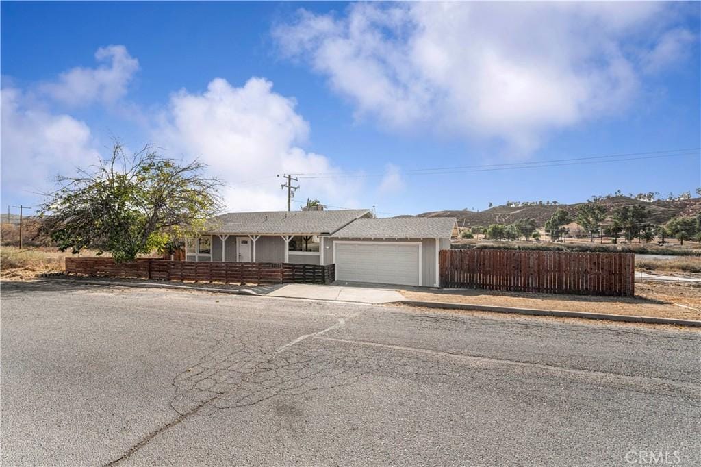 ranch-style home featuring a garage, fence, concrete driveway, and stucco siding