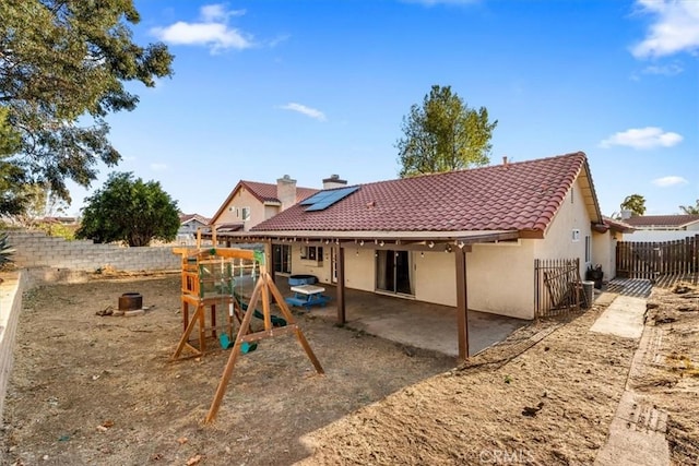 back of house featuring a playground, solar panels, and a patio