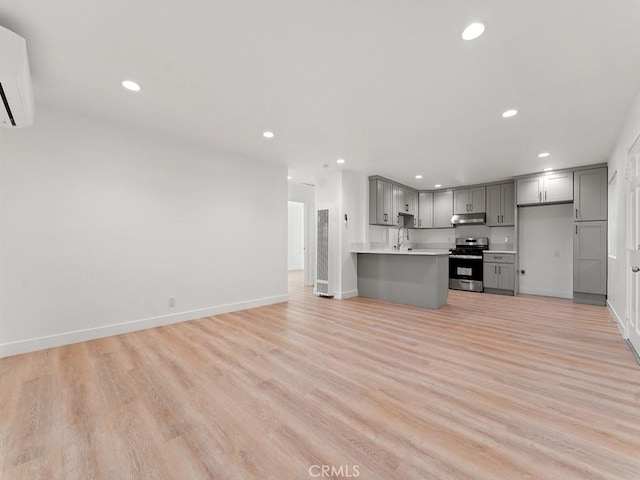 kitchen featuring a wall mounted AC, stainless steel stove, light hardwood / wood-style floors, and gray cabinets