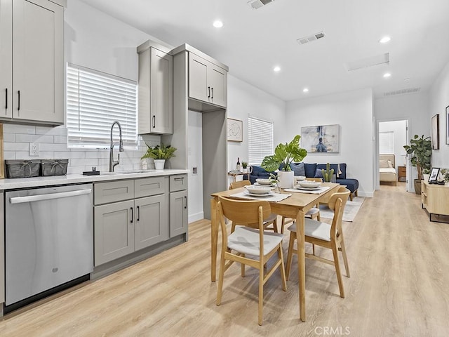 kitchen with light hardwood / wood-style floors, gray cabinets, decorative backsplash, dishwasher, and sink