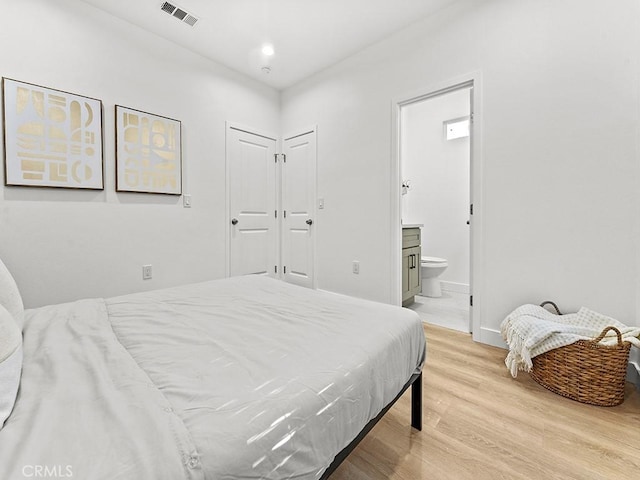 bedroom with light wood-type flooring, a closet, and connected bathroom