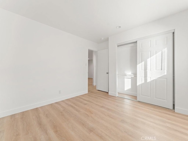 unfurnished bedroom with light hardwood / wood-style floors and a closet