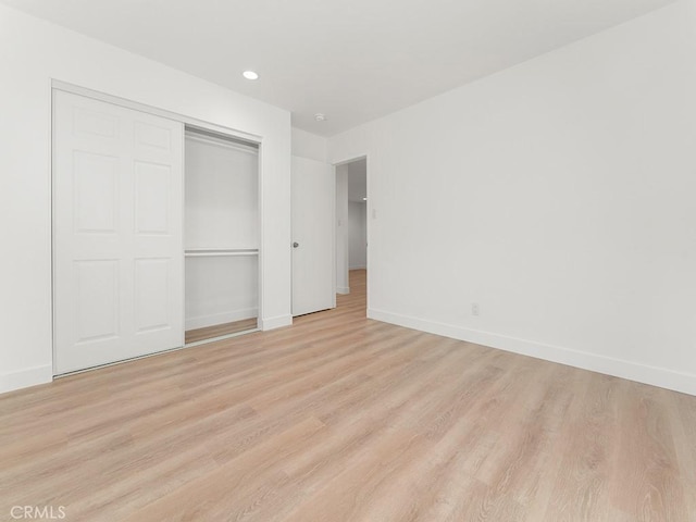 unfurnished bedroom featuring a closet and light wood-type flooring