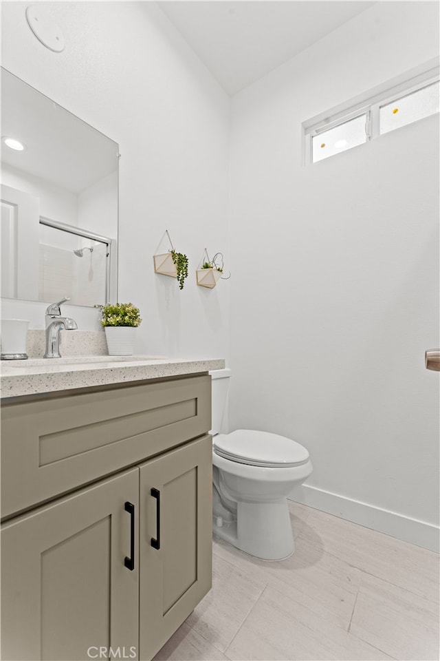 bathroom with a shower with shower door, vanity, and toilet