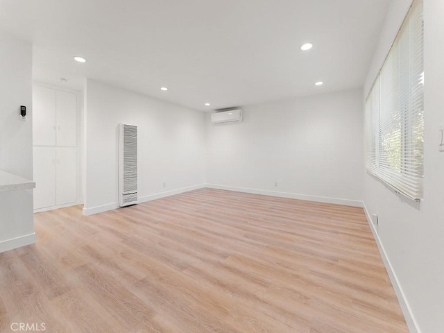 unfurnished room with light hardwood / wood-style flooring and a wall mounted air conditioner