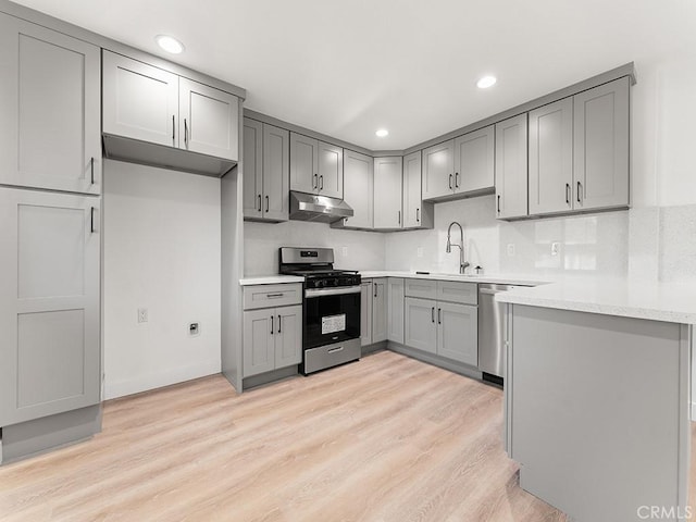 kitchen featuring light hardwood / wood-style flooring, stainless steel appliances, tasteful backsplash, sink, and gray cabinetry