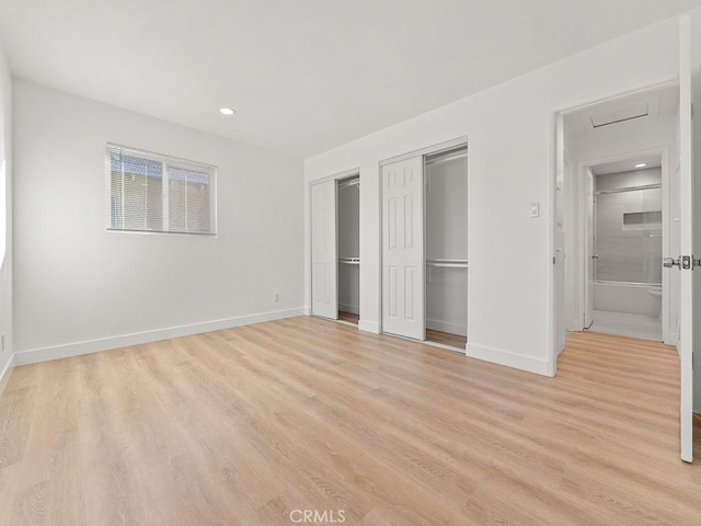 unfurnished bedroom with two closets and light hardwood / wood-style flooring