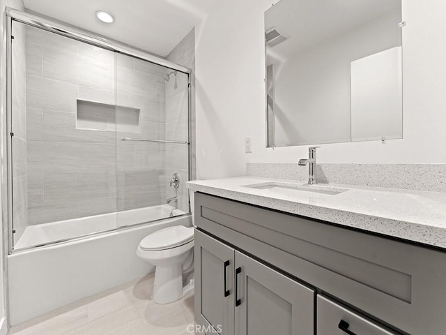 full bathroom with shower / bath combination with glass door, vanity, and toilet