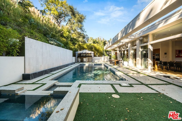 view of swimming pool featuring a patio area and an in ground hot tub