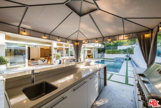 view of patio / terrace featuring a wet bar, an outdoor kitchen, and a gazebo