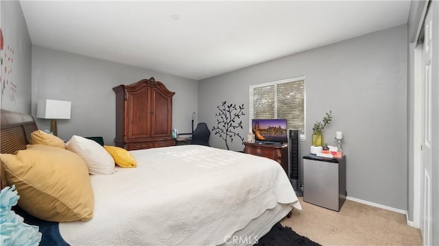 bedroom featuring freestanding refrigerator, baseboards, and light colored carpet