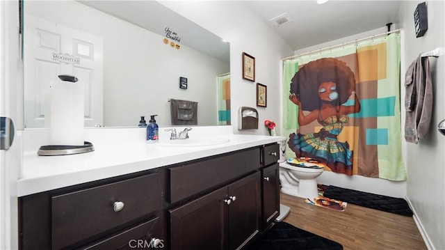 full bath featuring toilet, curtained shower, wood finished floors, and vanity