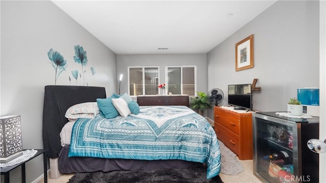 bedroom with wine cooler and light colored carpet