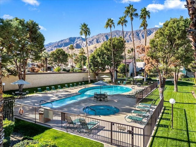 view of swimming pool with a mountain view, a community hot tub, a lawn, and a patio