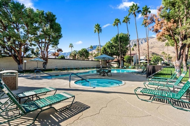 view of swimming pool featuring a mountain view, a community hot tub, and a patio