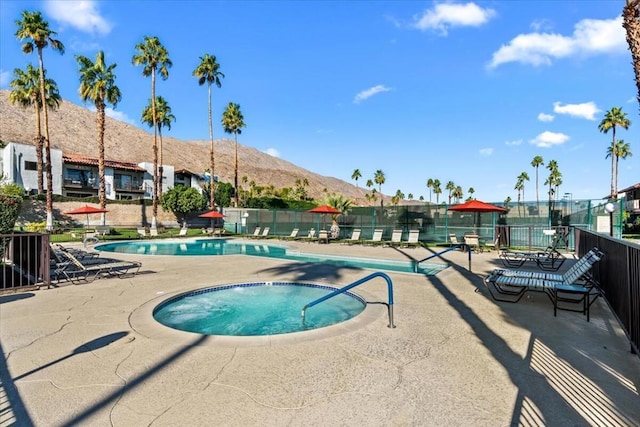 view of swimming pool featuring a patio area, a mountain view, and a community hot tub