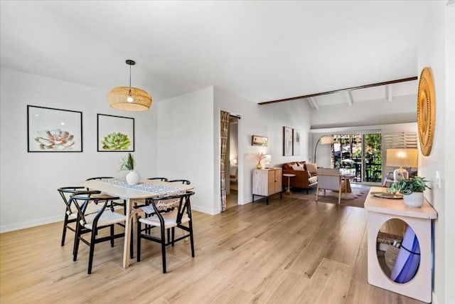 dining space with light wood-type flooring and beamed ceiling