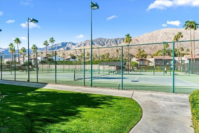 view of sport court with a mountain view and a yard