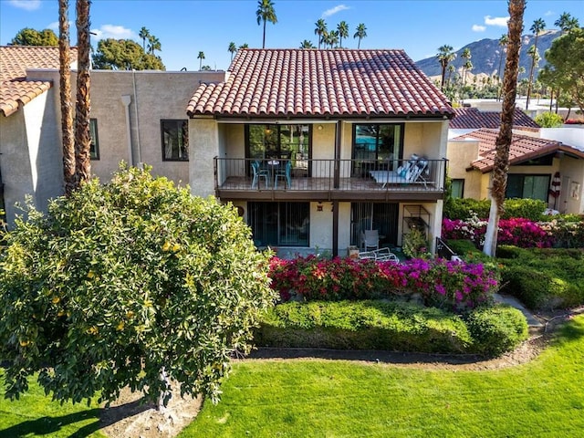 rear view of house featuring a mountain view, a lawn, and a balcony