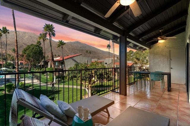 balcony at dusk featuring ceiling fan and a mountain view