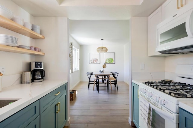 kitchen with decorative light fixtures, white appliances, light hardwood / wood-style flooring, light stone countertops, and white cabinets