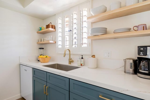 kitchen featuring light stone countertops, dishwasher, blue cabinetry, and sink