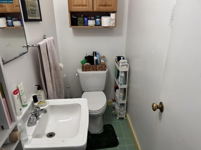 bathroom with toilet, tile patterned floors, and sink