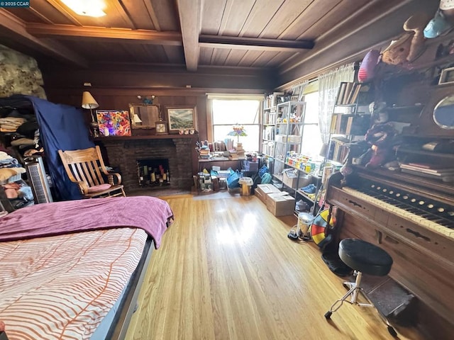 bedroom with a brick fireplace, wood ceiling, light hardwood / wood-style floors, and beam ceiling