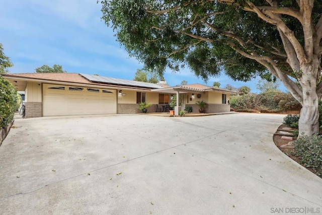 ranch-style home featuring a garage and solar panels