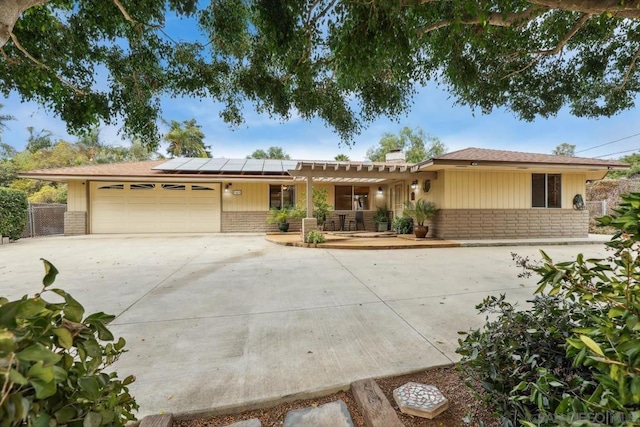 ranch-style home with a garage and solar panels