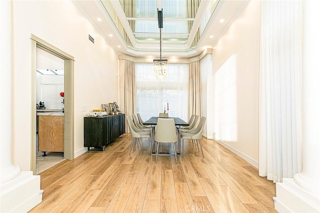 dining room with light hardwood / wood-style floors, a high ceiling, and a notable chandelier