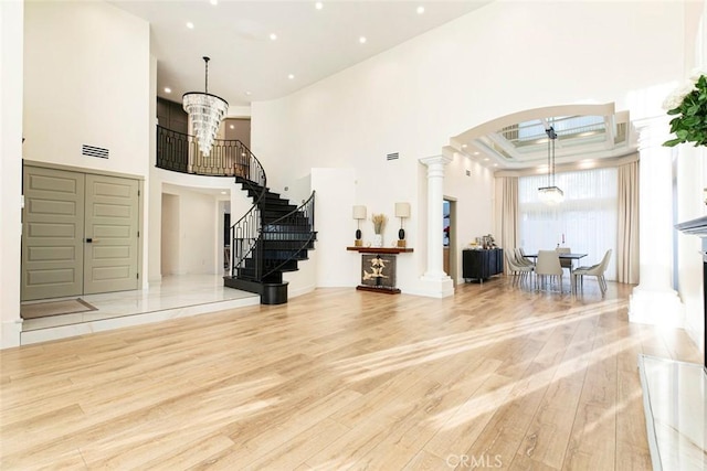 entryway featuring a towering ceiling, light hardwood / wood-style floors, and a chandelier