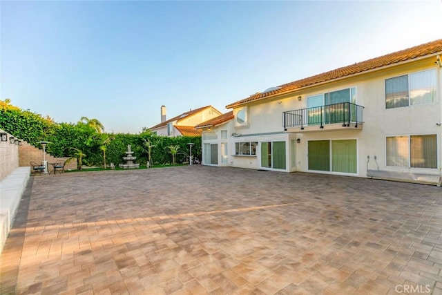 rear view of house featuring a balcony and a patio